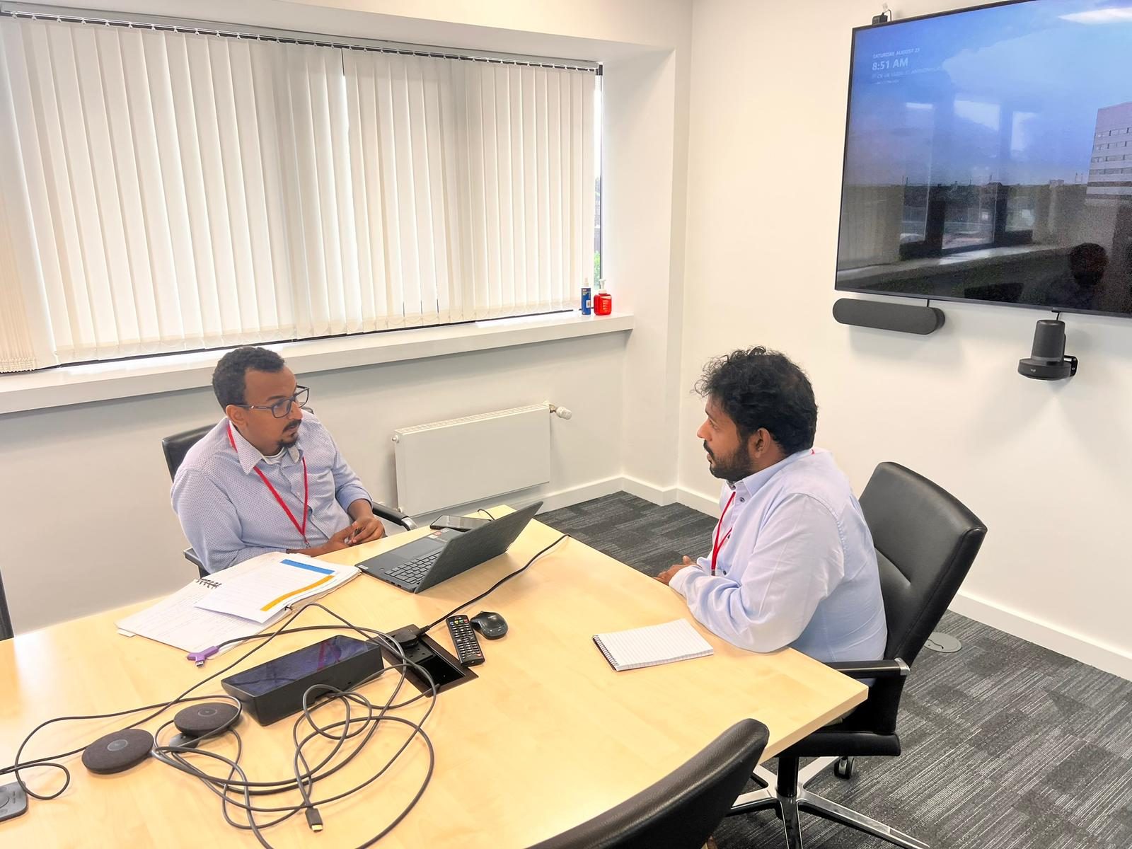 An examiner questions a candidate at a viva station under exam conditions